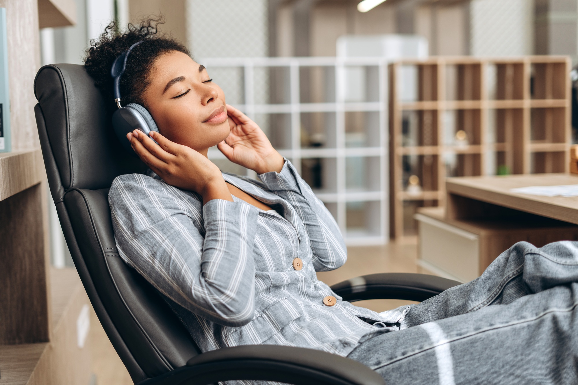 Businesswoman listening to music on headphones in office chair