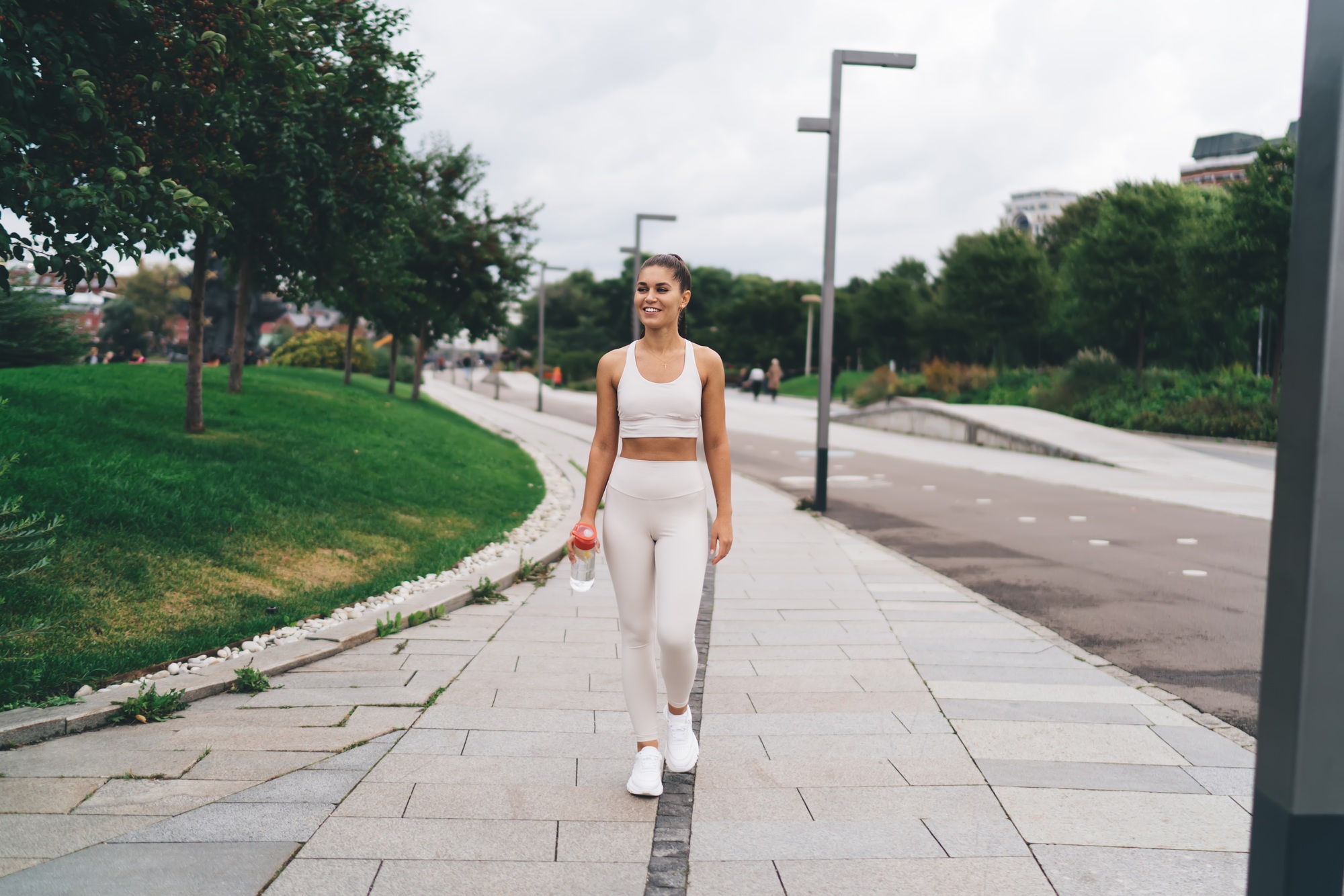 Happy sportswoman walking in park