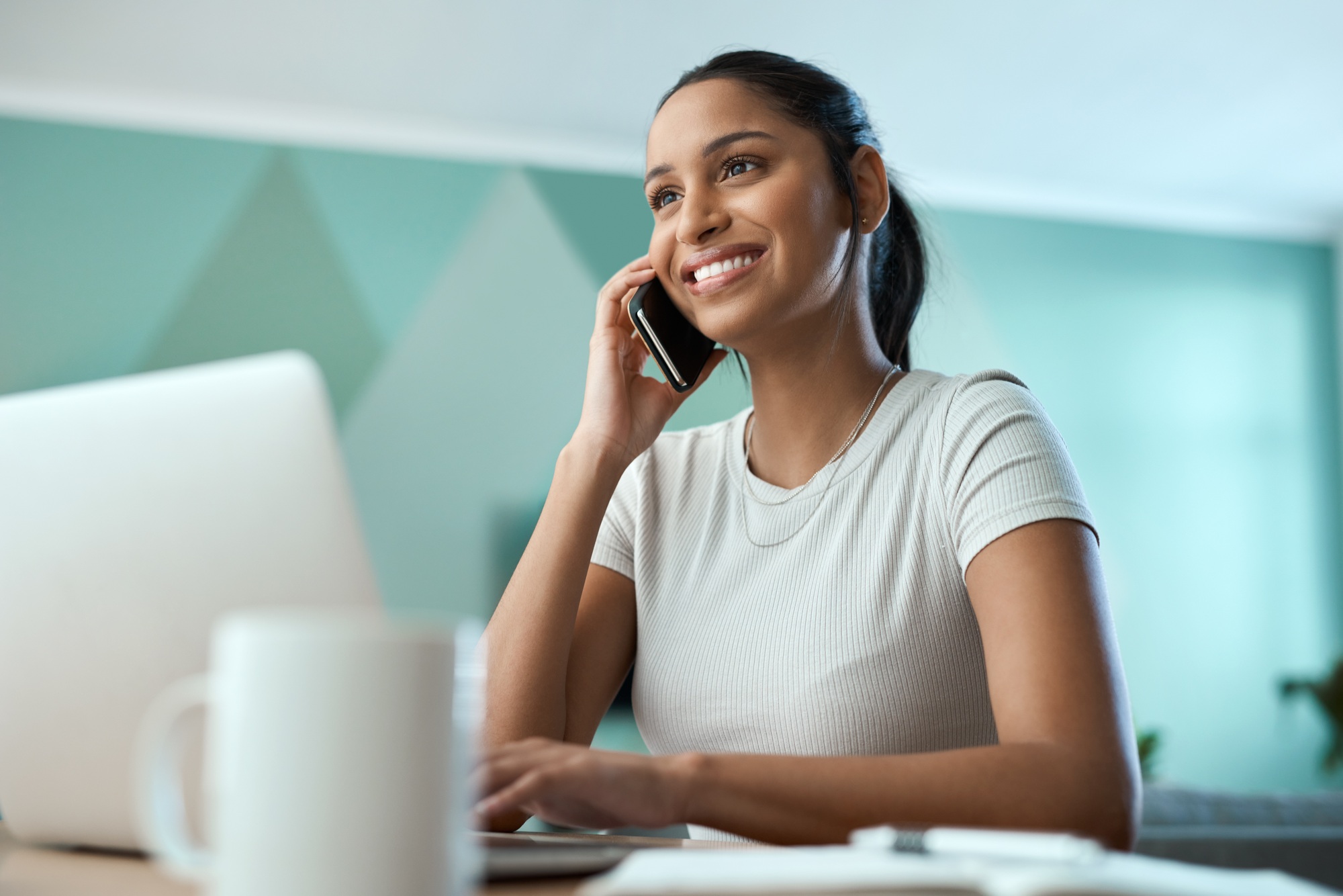 Shot of a young woman using a laptop while on a call at home