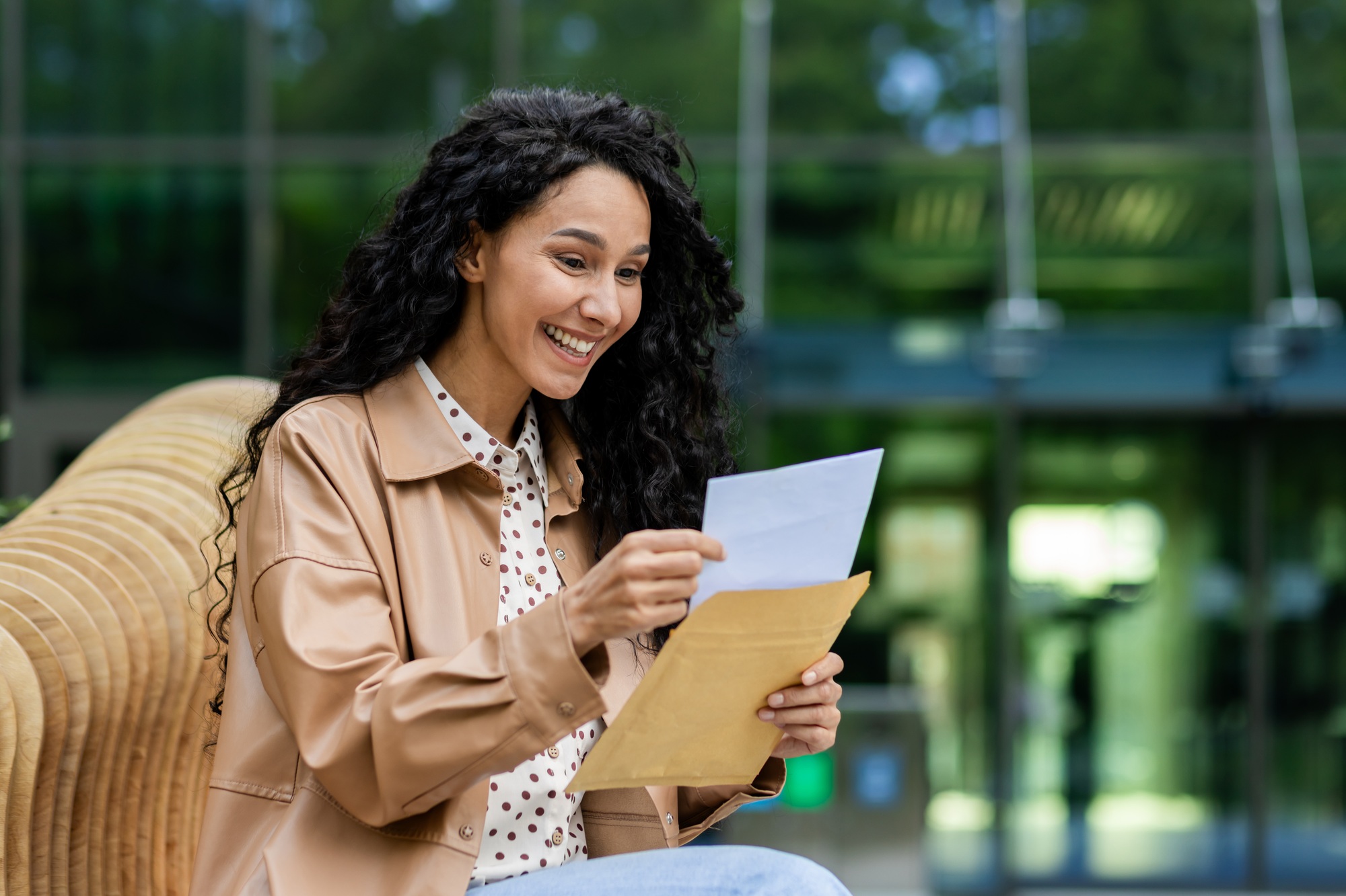 Woman reading a letter outdoor, relaxed setting with nature backdrop